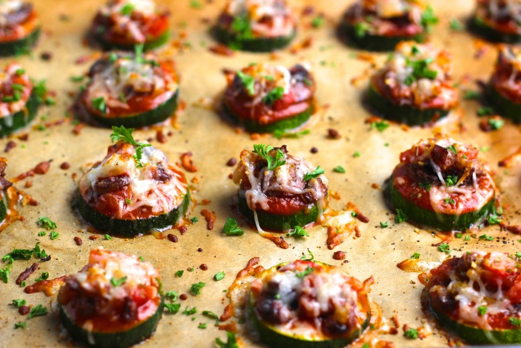 A parchment-lined tray filled with zucchini pizza bites.