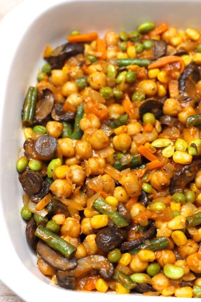 A white casserole dish filled with vegetables and chickpeas.