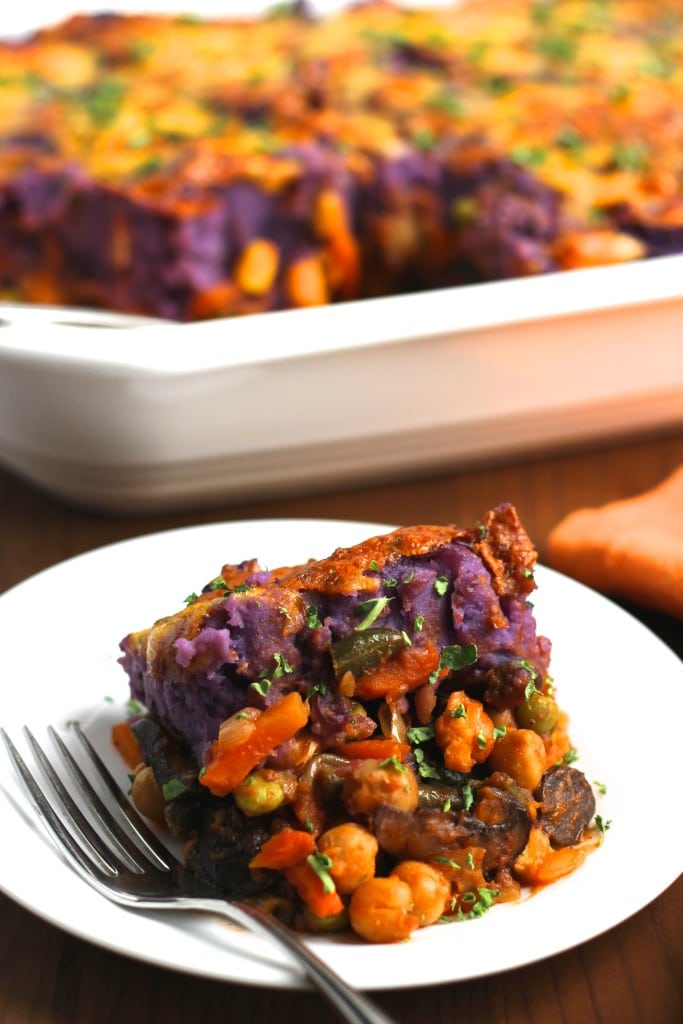 A small white plate with a slice of vegetable pie and a fork with the casserole int he background. 