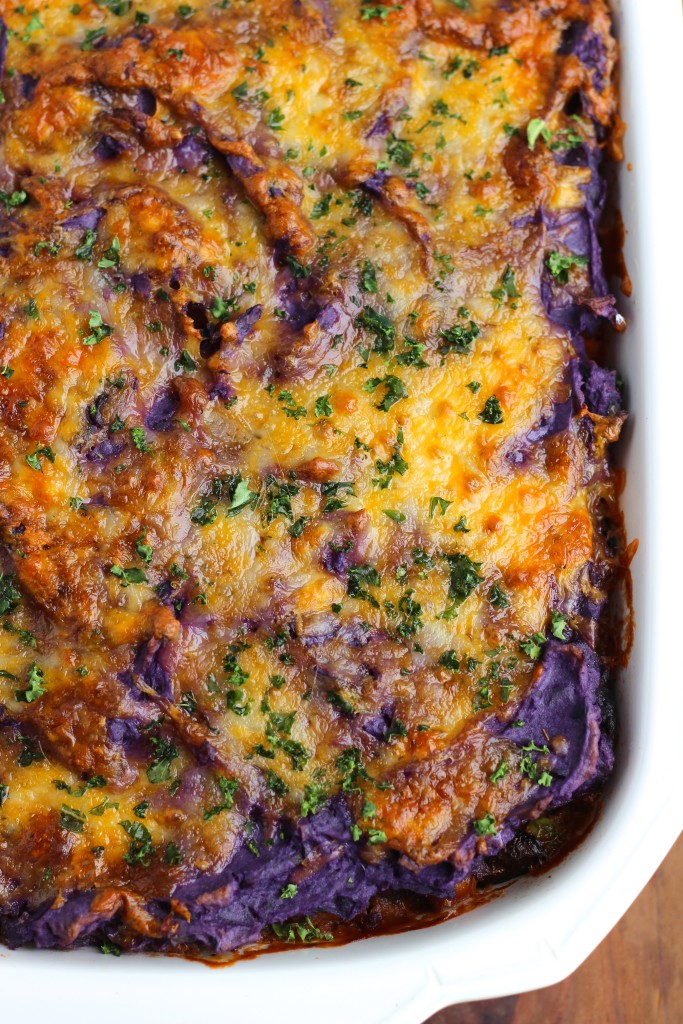 Overhead view of a white casserole dish filled with vegan shepherd's pie on a rustic background.