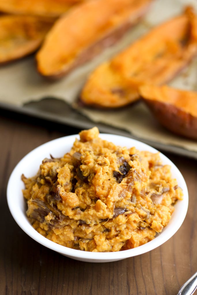 A white bowl filled with mashed sweet potatoes on a rustic background. 