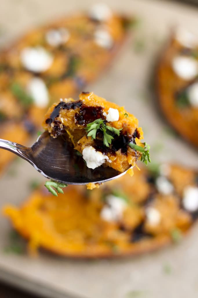 A spoonful of mashed sweet potatoes over a tray of twice baked stuffed sweet potatoes. 