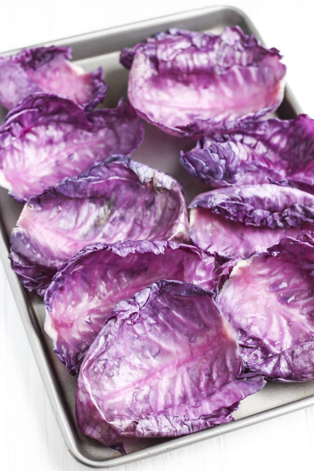 A tray full of cooked red cabbage leaves on a white background.