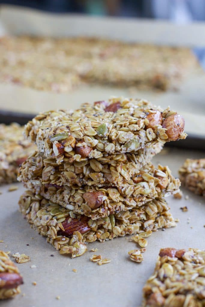 Four granola bars stacked on top of each other on top of a parchment-lined tray.