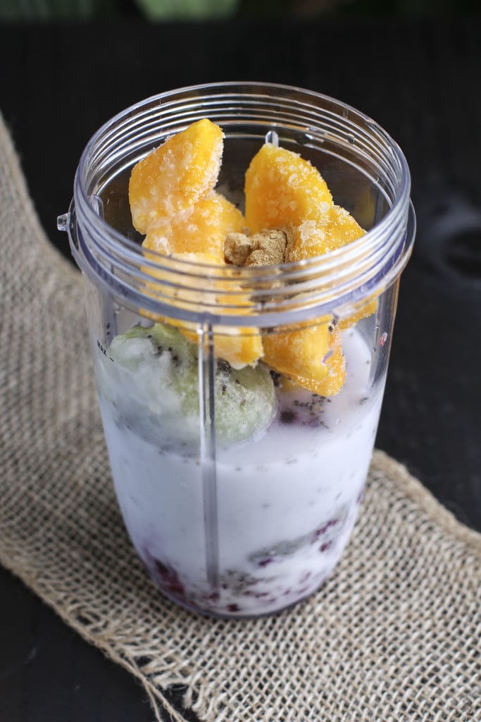 Frozen fruit in a plastic blender cup on a piece of burlap.