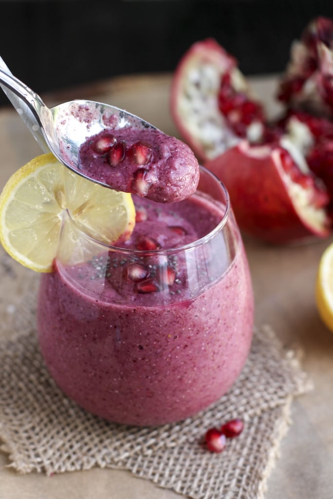 A spoon dipping into a cup filled with a smoothie on top of a piece of burlap.