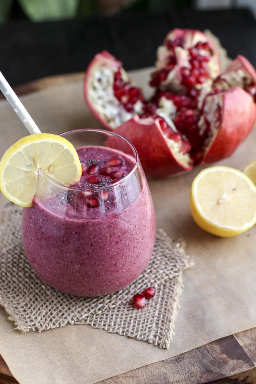 A cup filled with a pink smoothie in a glass cup on top of a piece of burlap. 