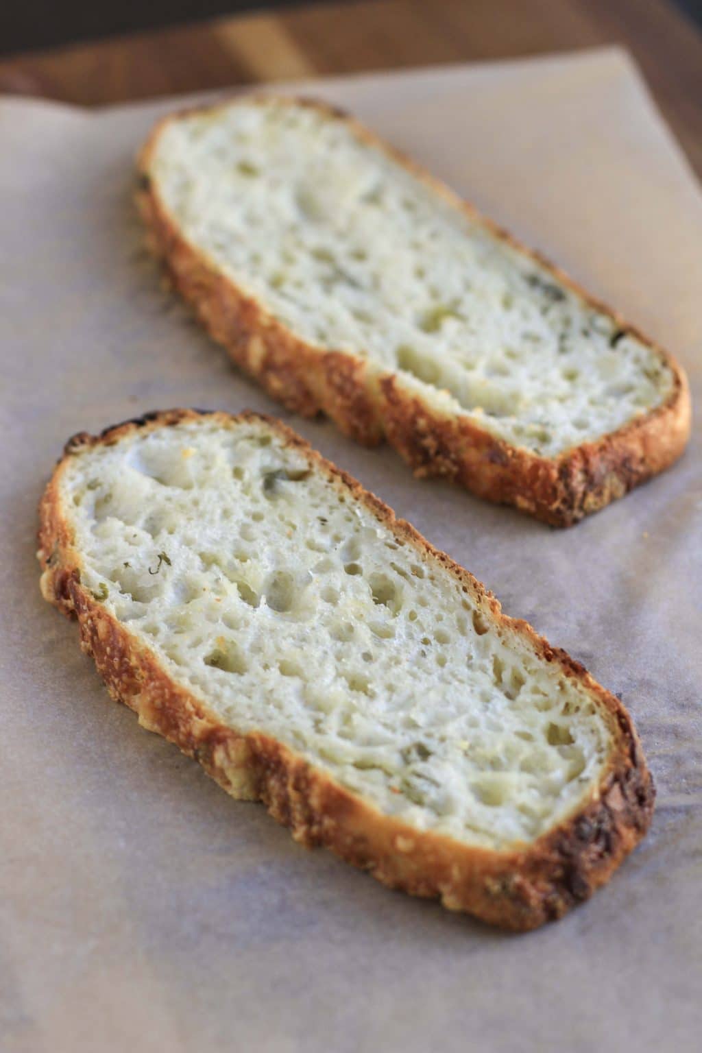 Two slices of bread on a piece of parchment paper. 