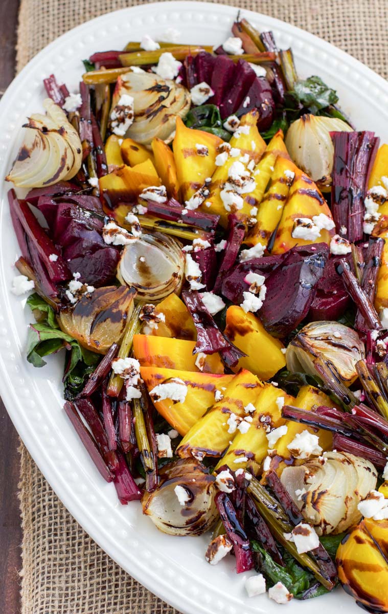 Overhead shot of a white platter filled with roasted beetroot salad on top of burlap runner.