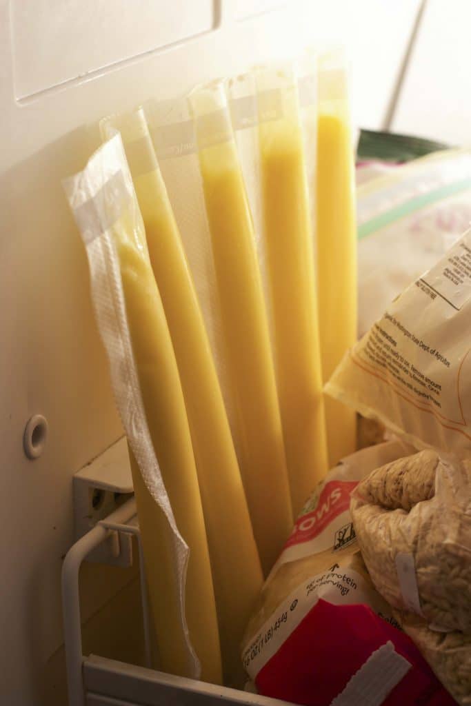 Yellow popsicles leaning up against the wall in a freezer. 