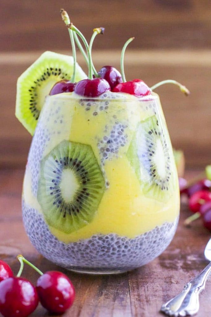 A cup filled with chia seed pudding and fruit with a rustic wood background. 