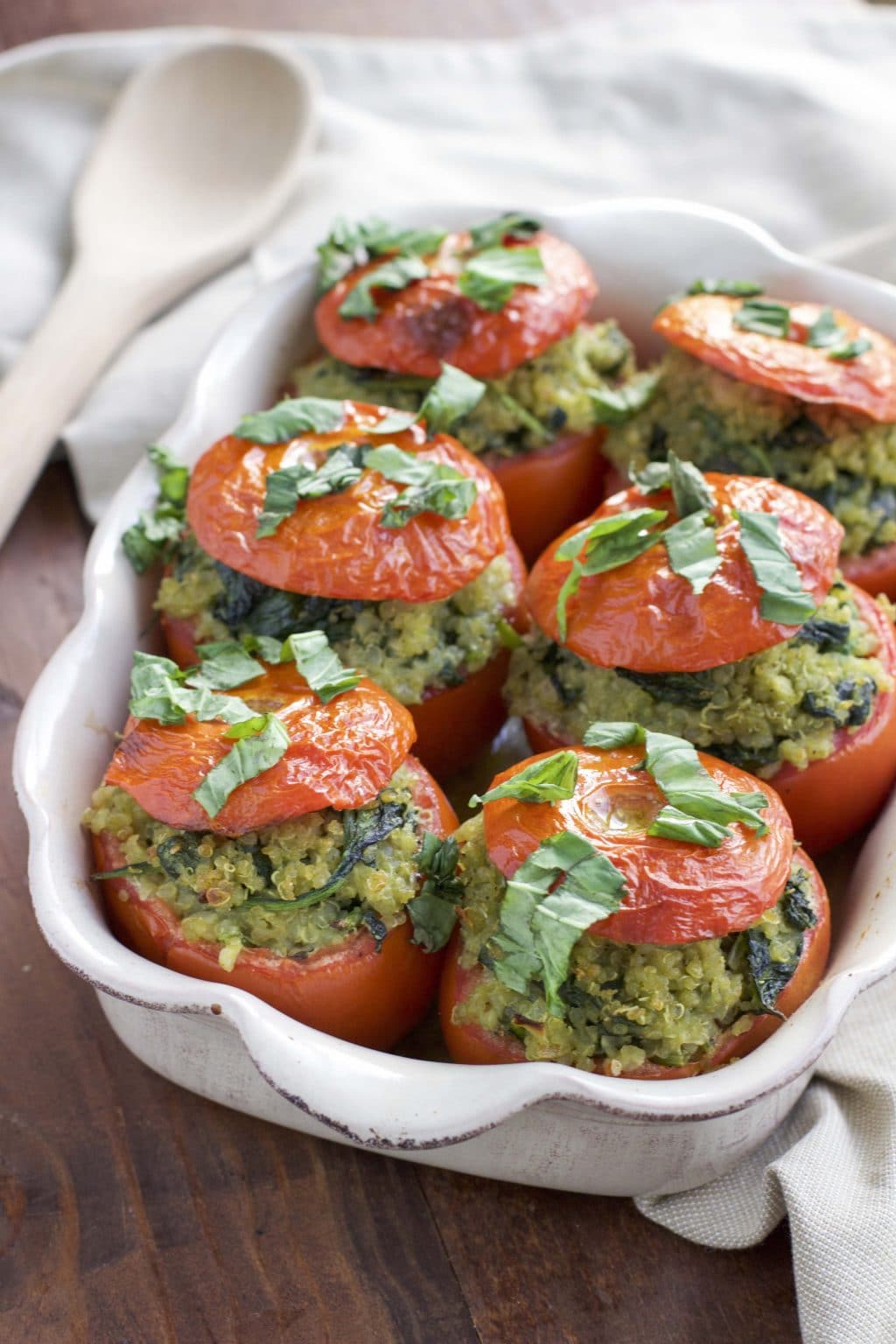 Roasted stuffed tomatoes in a white casserole dish on a rustic background.