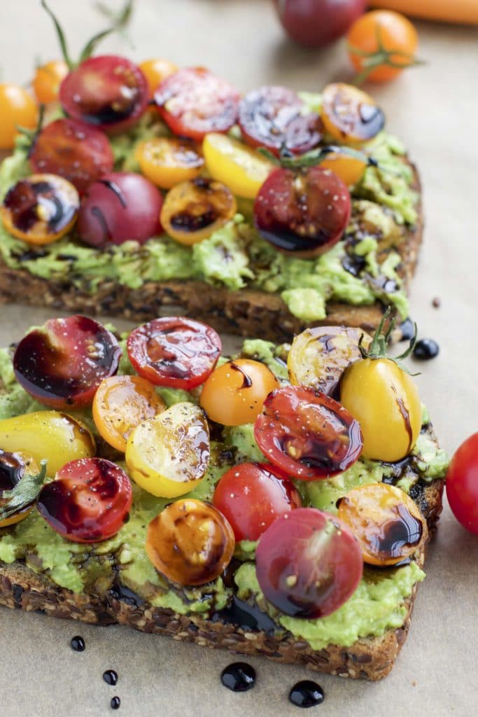 Close up view of two slices of avocado toast with cherry tomatoes. 