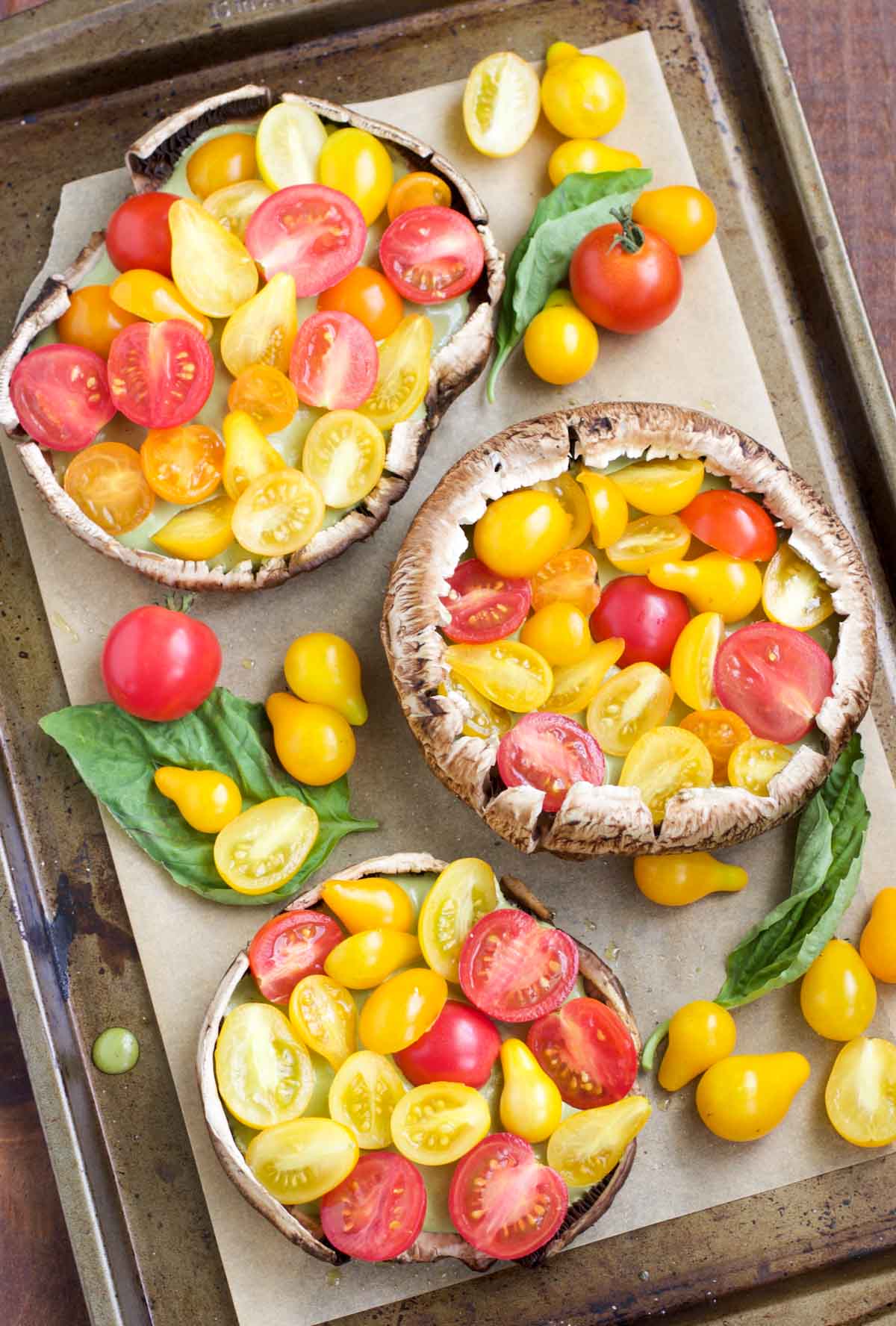 Overhead view of a large tray filled with mushrooms, basil and cherry tomatoes. 