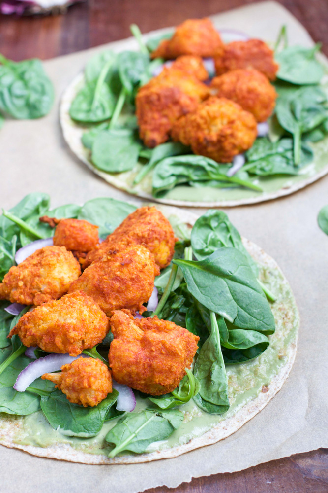 Two cauliflower wraps laying open faced on a piece of parchment paper.