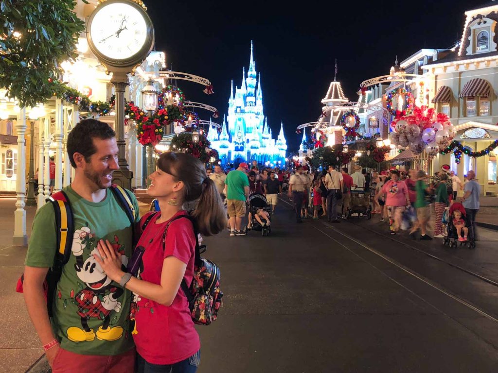 A happy couple posing on Main Street USA in front of Cinderella Castle at the Disney Christmas Party. 