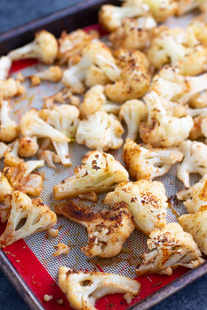 A lined sheet pat full of roasted seasoned cauliflower florets. 