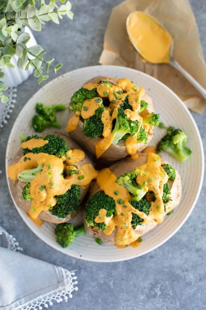 A plate filled with potatoes stuffed with broccoli and cheese sauce on a gray background. 