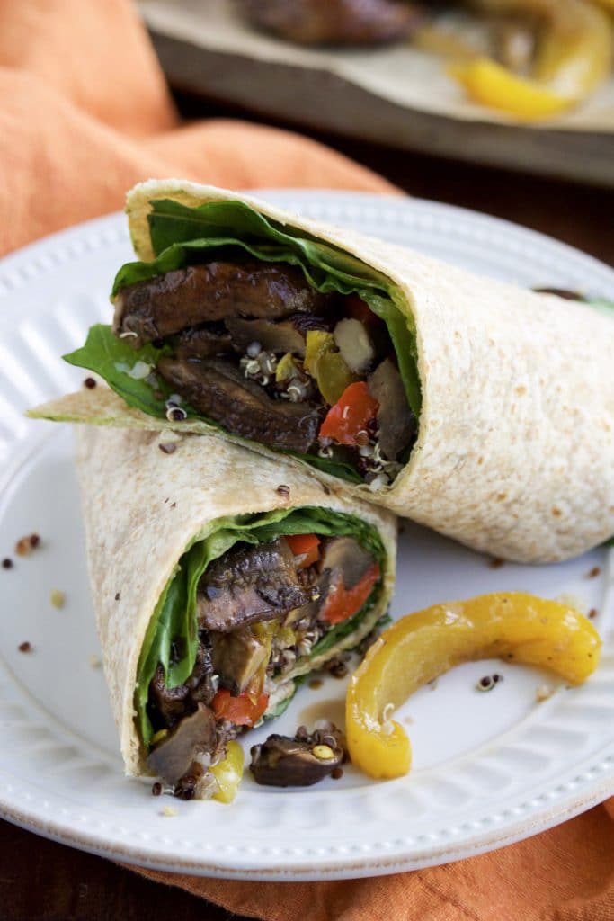 Close up view of a vegan wrap cut in half and stacked on top of each other on a white plate. 