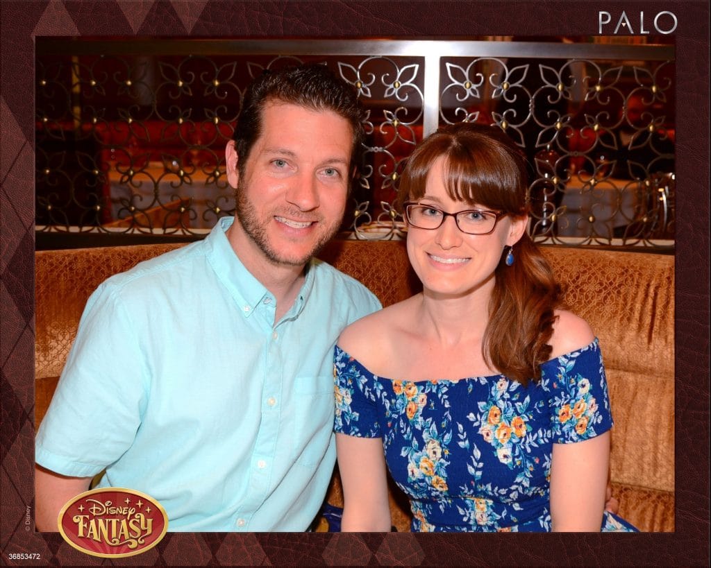 A man and woman smiling and sitting in a booth at Palo while eating dinner on the Disney Fantasy.