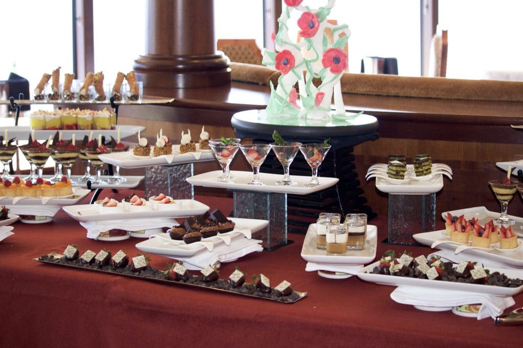 A table filled with multiple plate of small desserts at Palo on the Disney Fantasy.