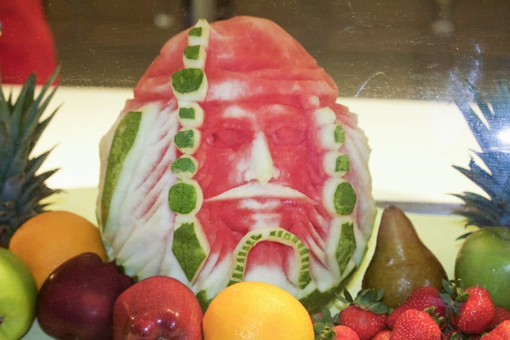 A watermelon is carved to look like Captain Jack Sparrow next to pieces of fruit. 