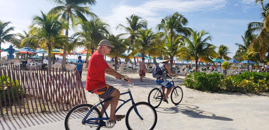 Two men riding bikes down the street on Castaway Cay.