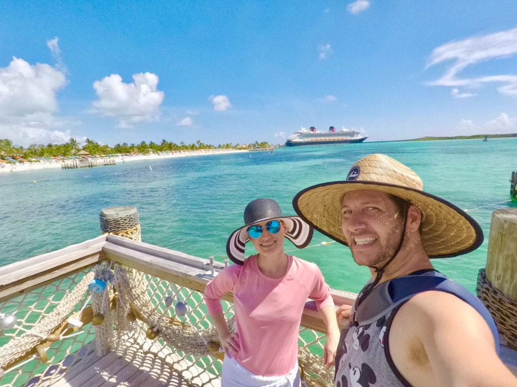 A man and woman smiling while standing on a dock over the water at Castaway Cay.