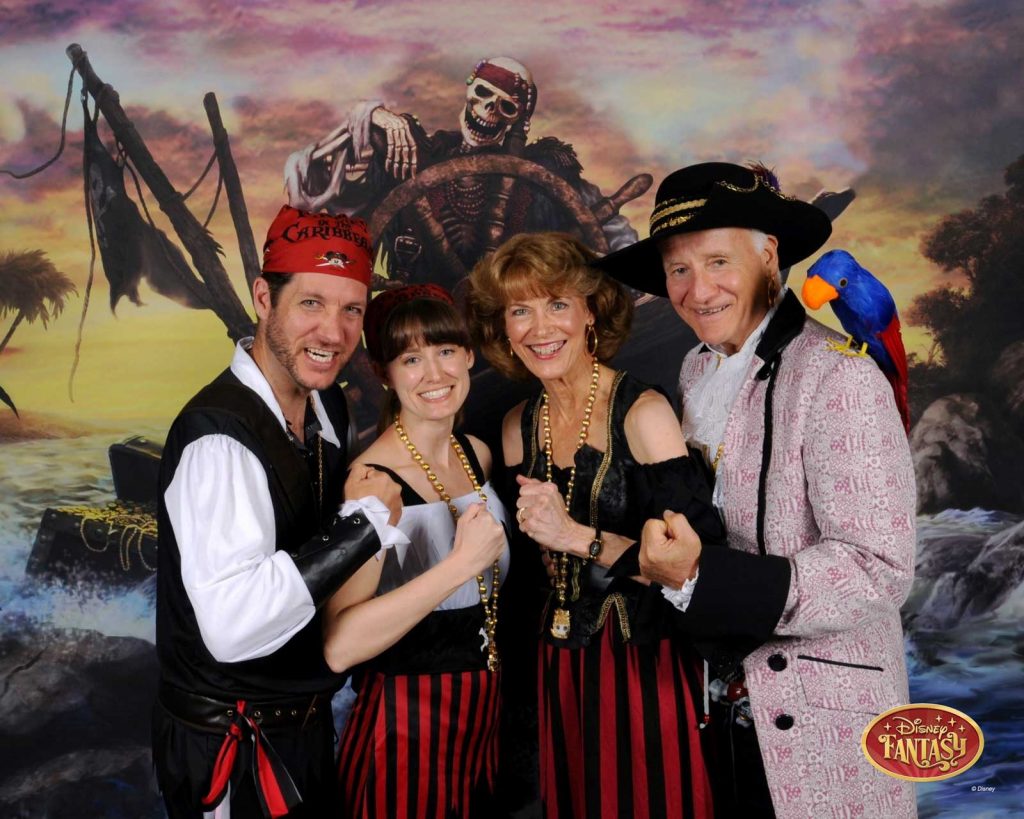 A family of four dressed like pirates in front of a pirate themed backdrop. 