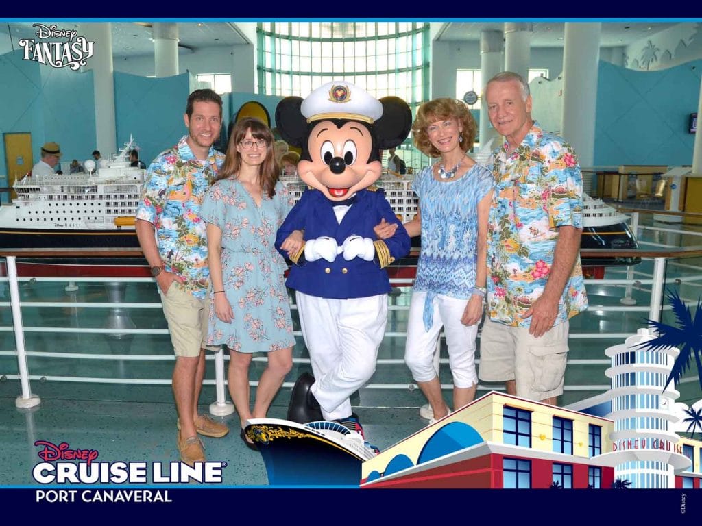 A family smiling and posing with Mickey Mouse at the Port Canaveral terminal.