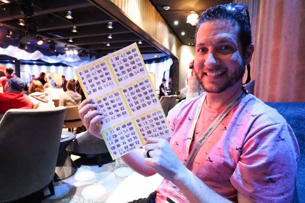 A man holding bingo cards after playing on bingo on a Disney cruise. 