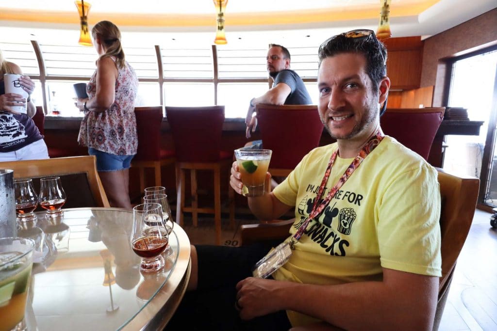 A man holding a drink at a beverage seminar on a Disney cruise. 