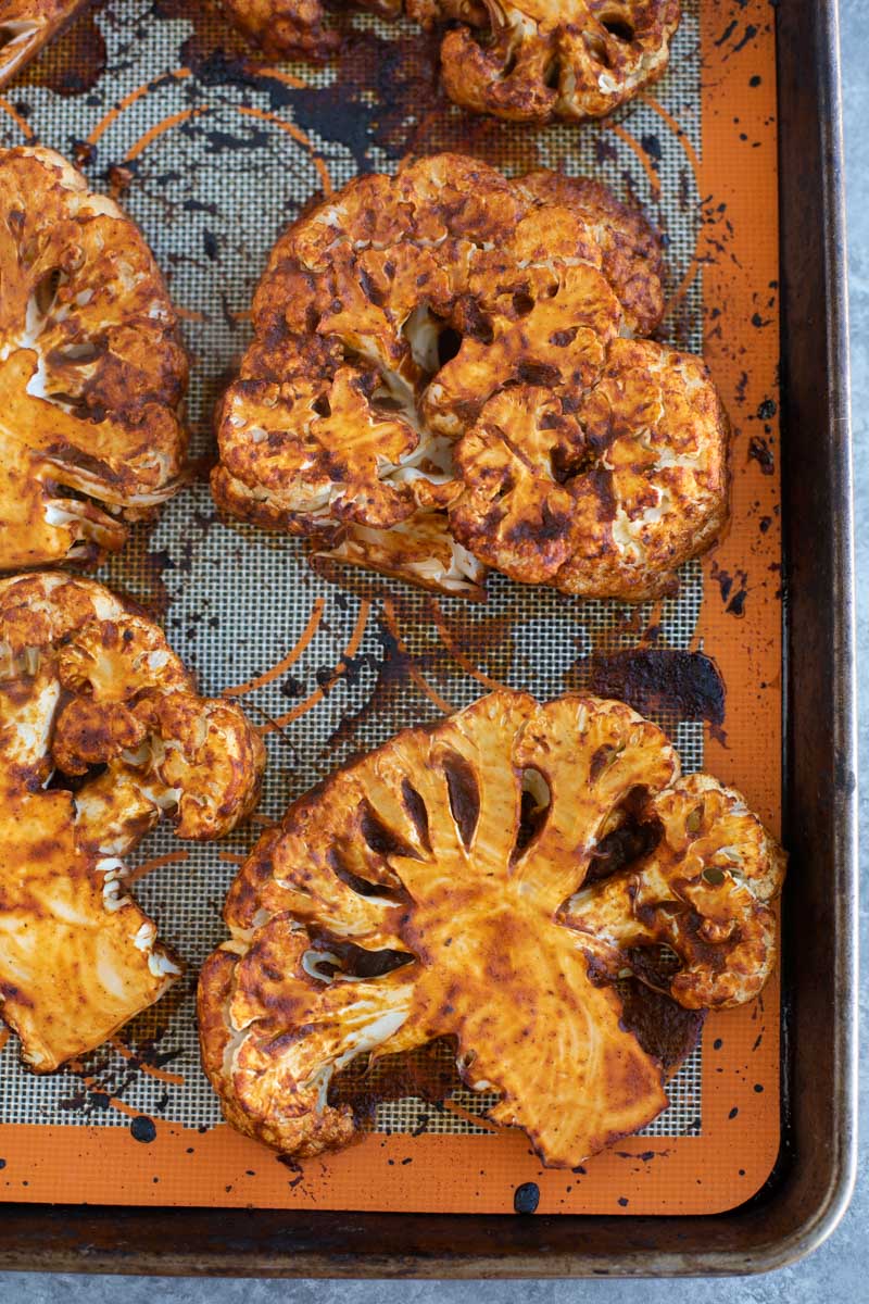 A close up view of cauliflower steaks on a baking tray.