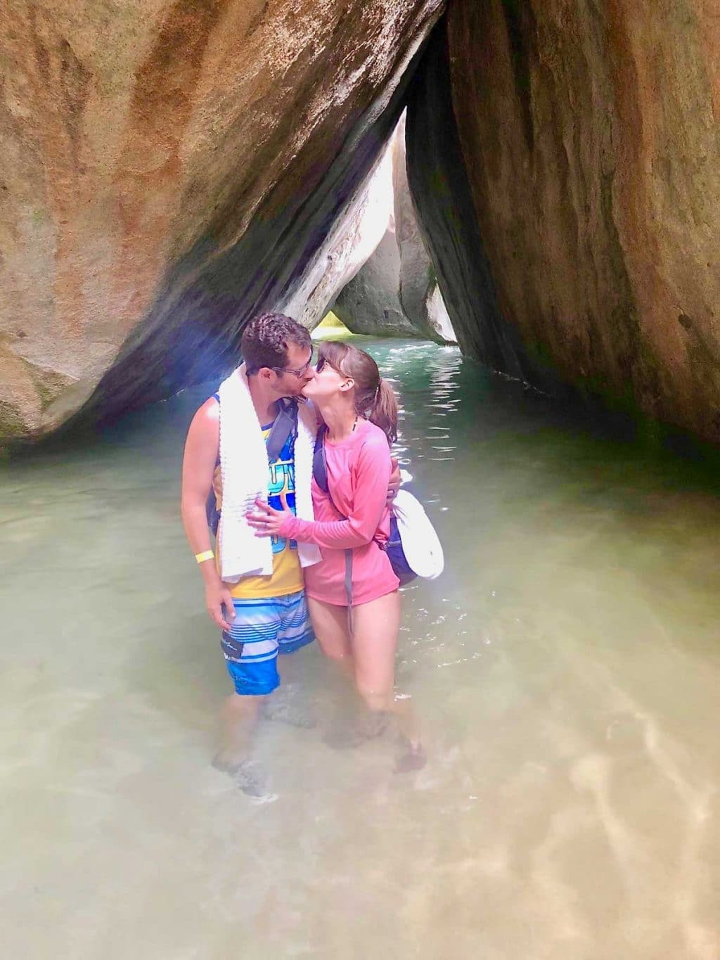 A man and woman kissing in front of the cathedral at The Baths in Tortola. 