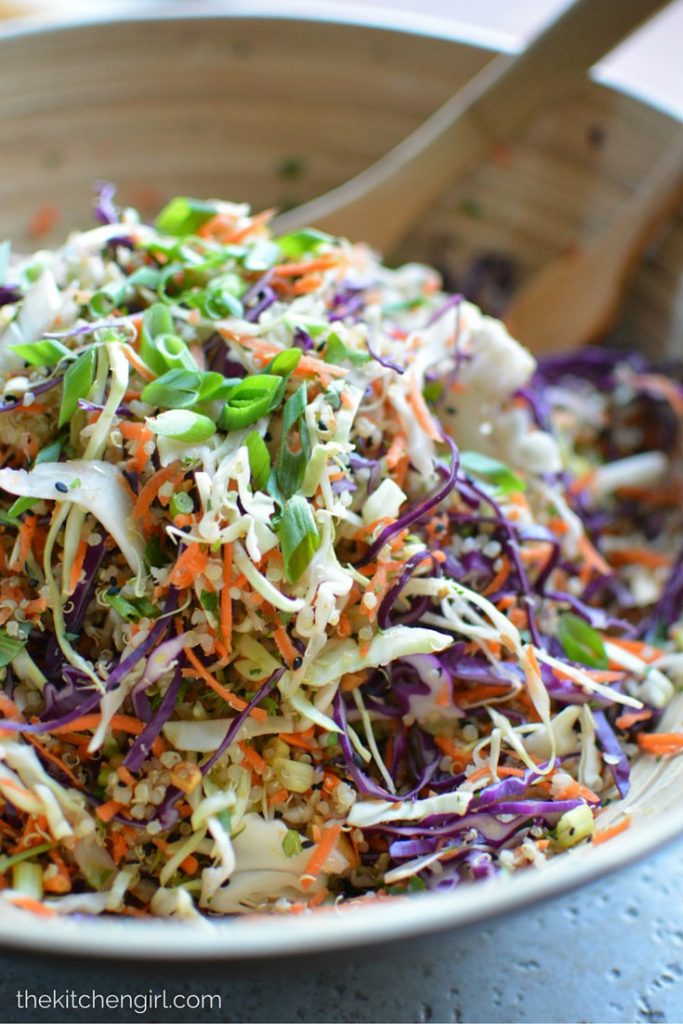 A bowl filled with cabbage quinoa salad and topped with green onions. 