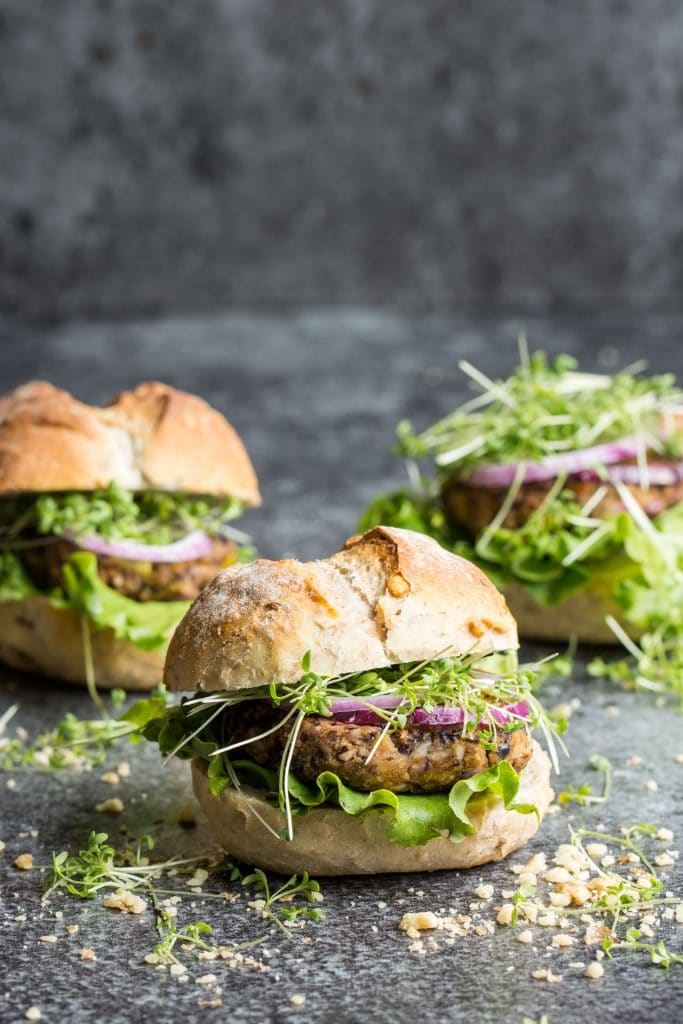 Three vegan black bean burgers on a dark gray background. 