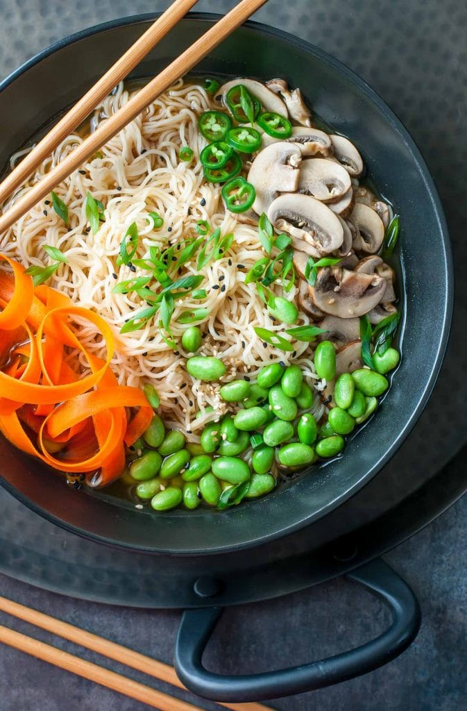 A black bowl filled with vegan ramen on a dark background. 