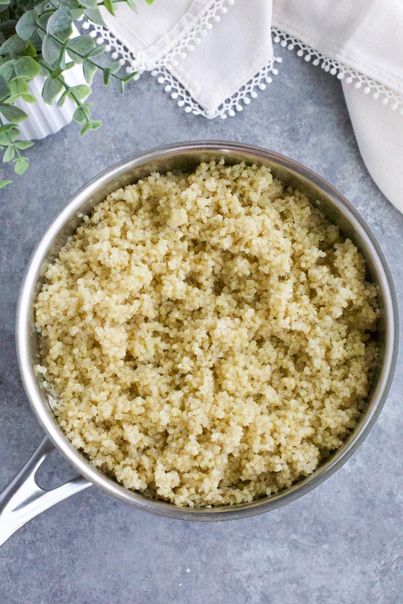 A small pan filled with cooked quinoa on a gray background. 