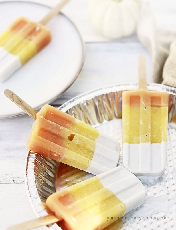 Four vegan candy corn colored popsicles resting on a tin foil pan. 