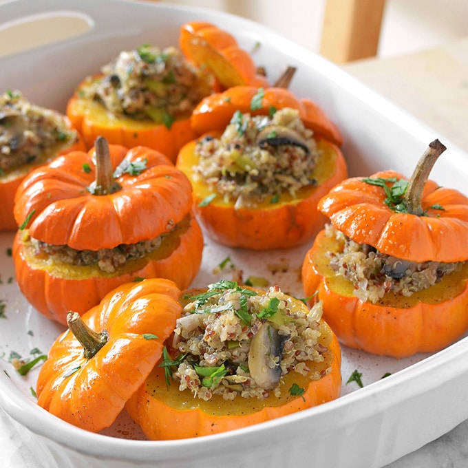 A large white casserole dish filled with 6 mini stuffed pumpkins.