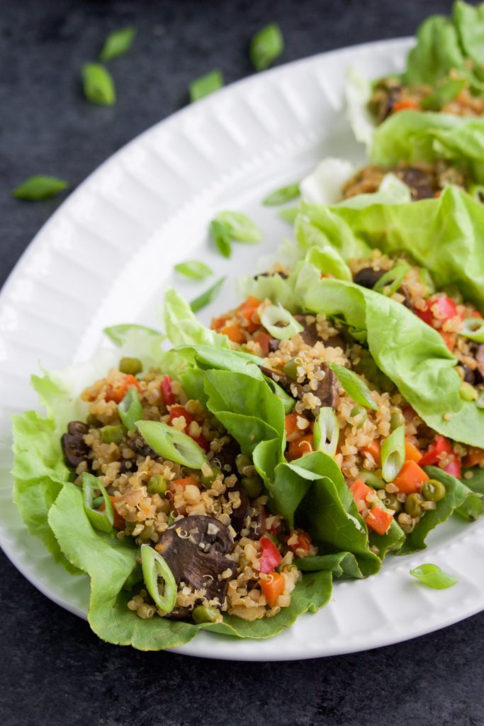 A large white platter filled with lettuce wraps on a dark background. 