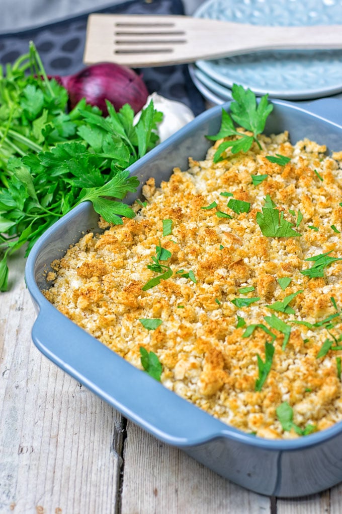 A blue casserole dish filled with low-carb green bean casserole and fresh herbs on the side. 