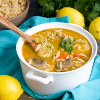 Soup in a white bowl on top of an aqua napkin next to a few lemons.