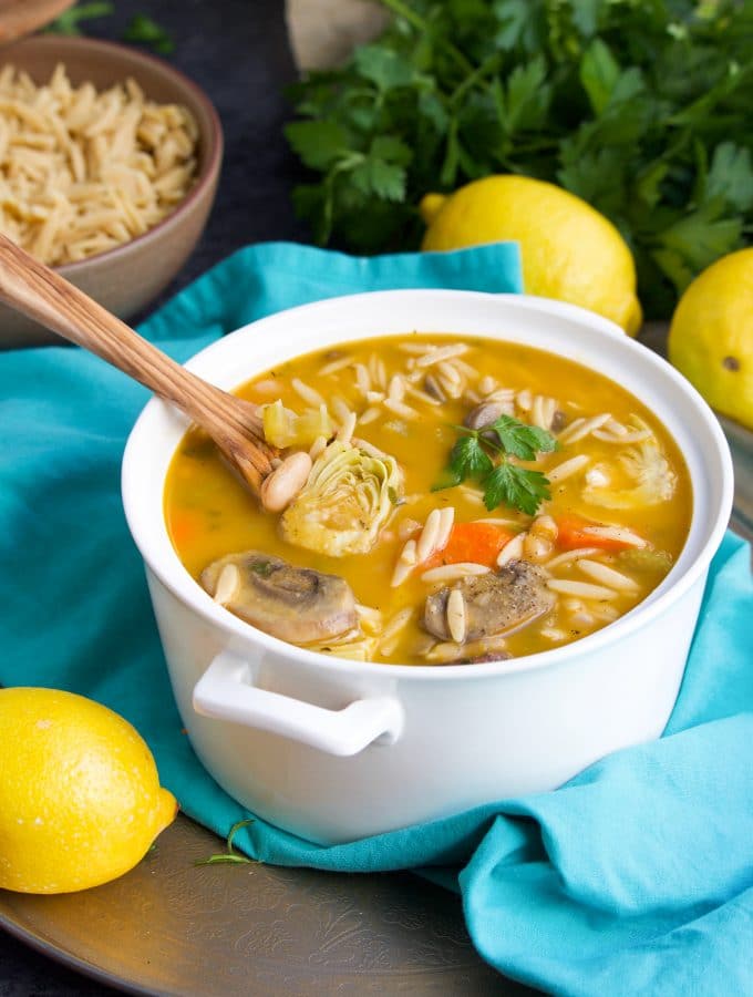 Soup in a white bowl on top of an aqua napkin next to a few lemons.