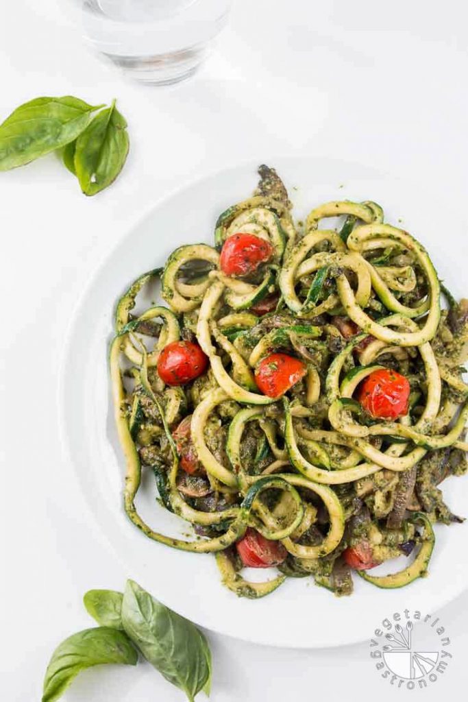 Low-carb vegan pesto zucchini noodles in a white bowl on a white background.