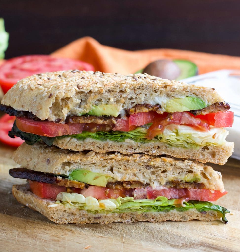 Two halves of a vegan sandwich stacked on top of each other on a rustic background. 