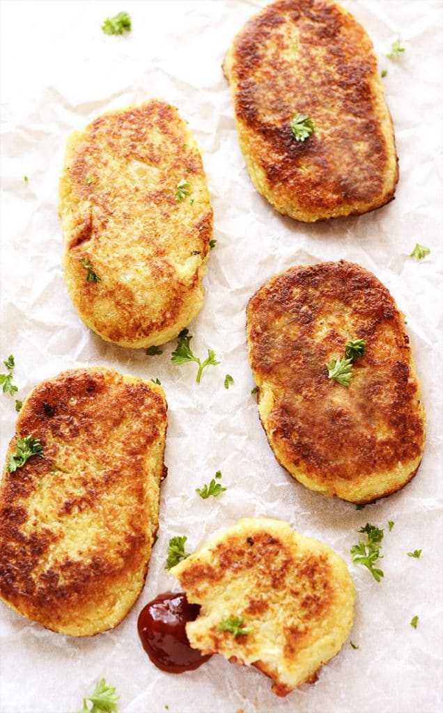 Low-carb vegan cauliflower hash browns resting on a textured white background. 
