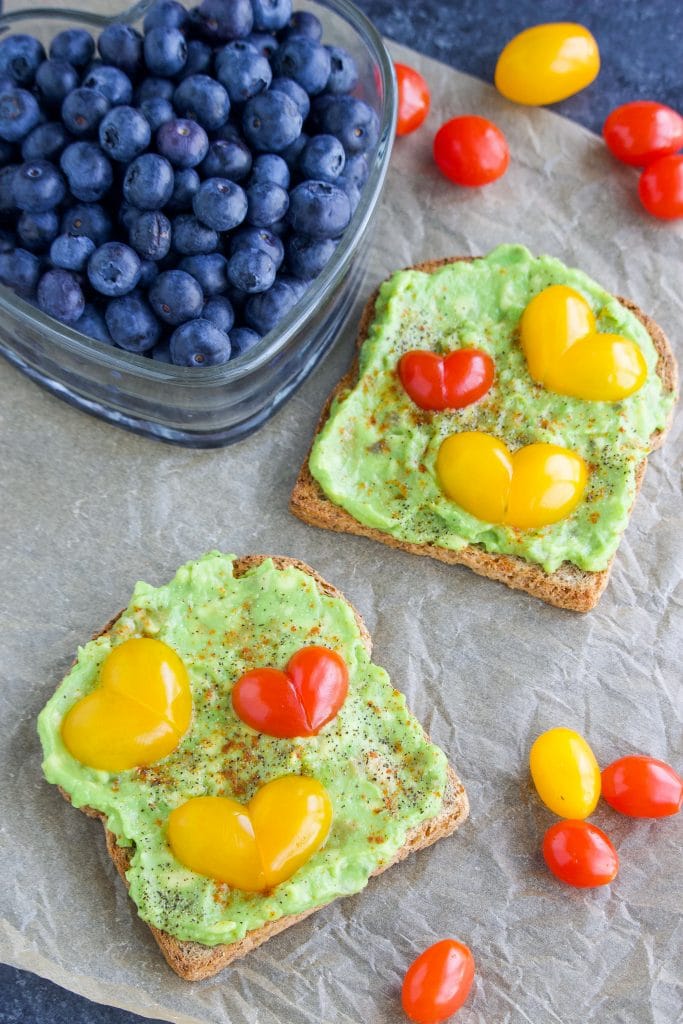 Two slices of toast next to a container of blueberries on a piece of parchment paper. 