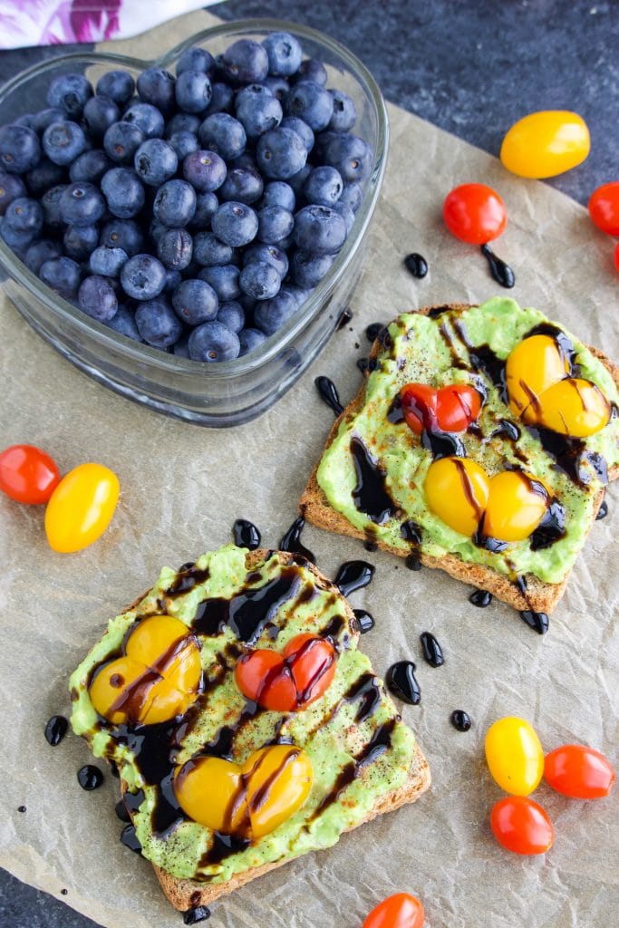 Two slices of toast and a heart-shaped container of blueberries on top of a piece of parchment paper. 