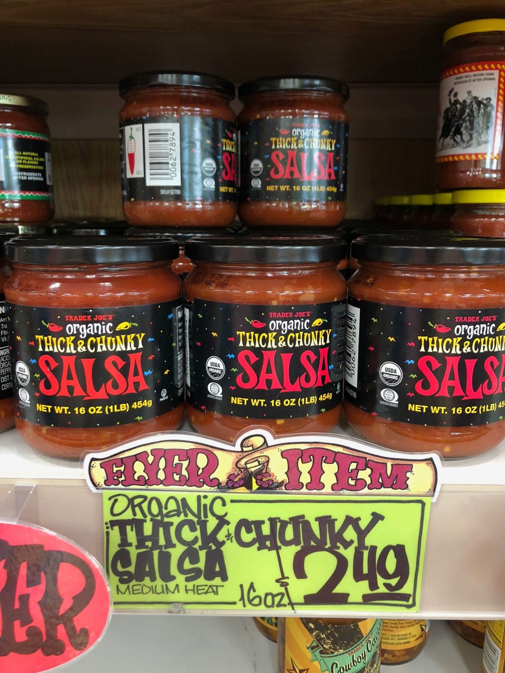 Multiple glass jars of organic thick & chunky salsa on a shelf at Trader Joe's. 